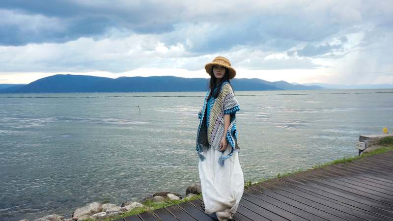 Backpacker wearing a compact travel poncho in a misty mountain landscape